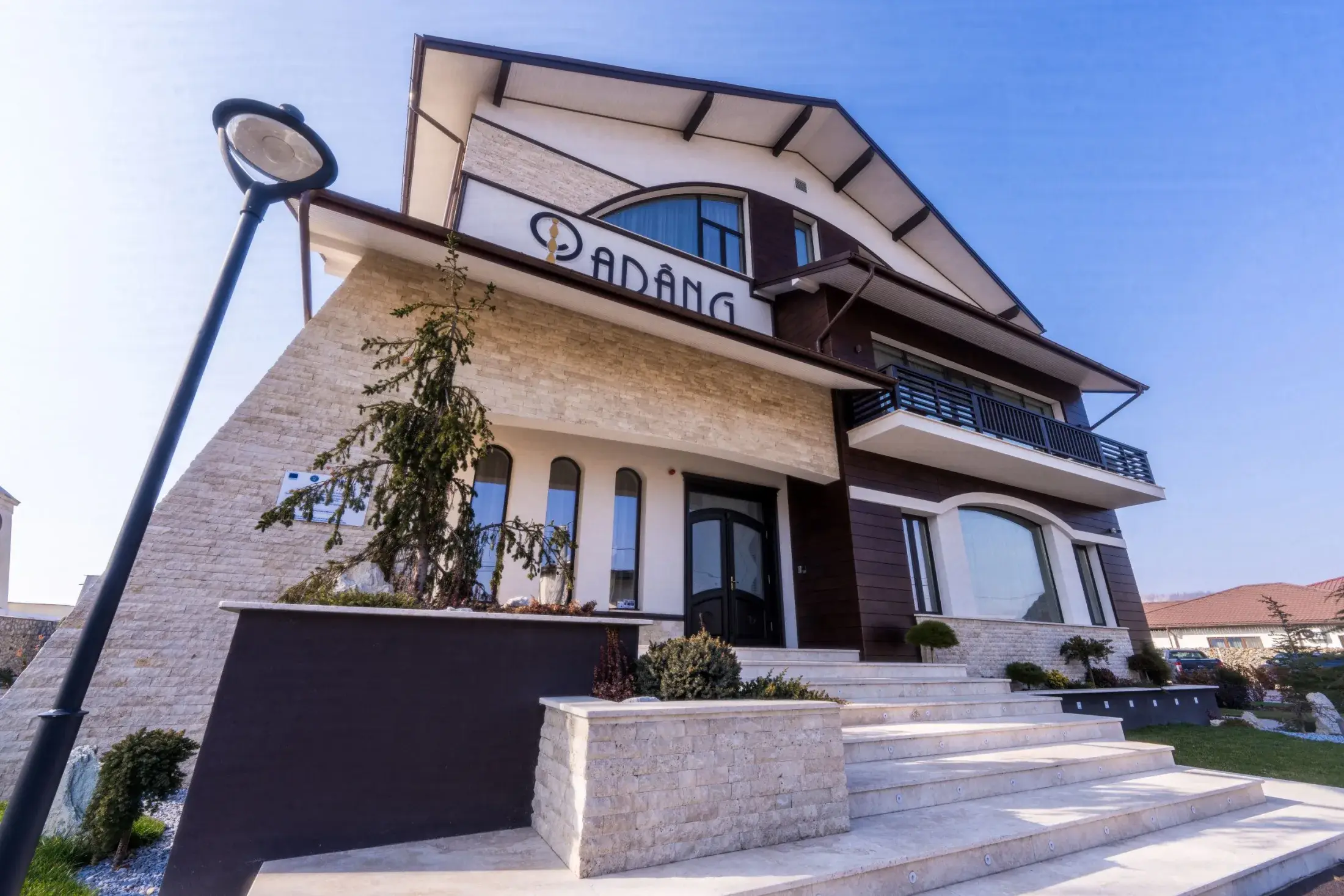 Intrarea pensiunii văzută de jos, cu scări de piatră și firma Parâng