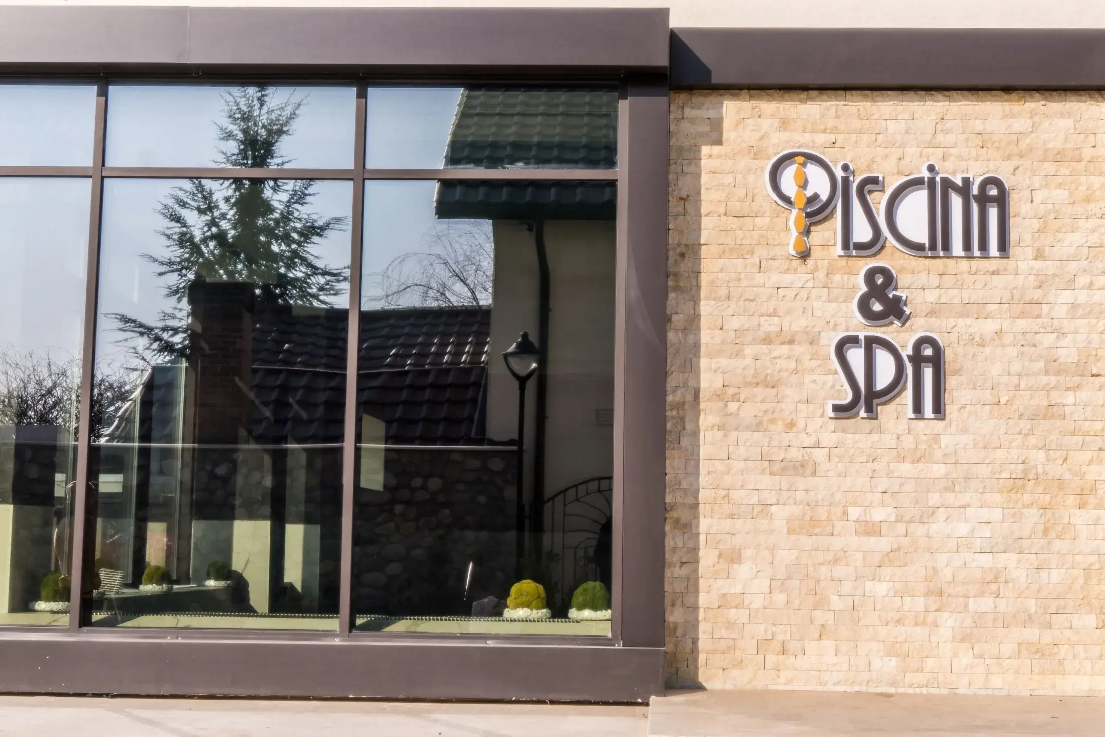 Intrarea în zona de piscină, cu inscripția Piscina & SPA pe zidul de piatră