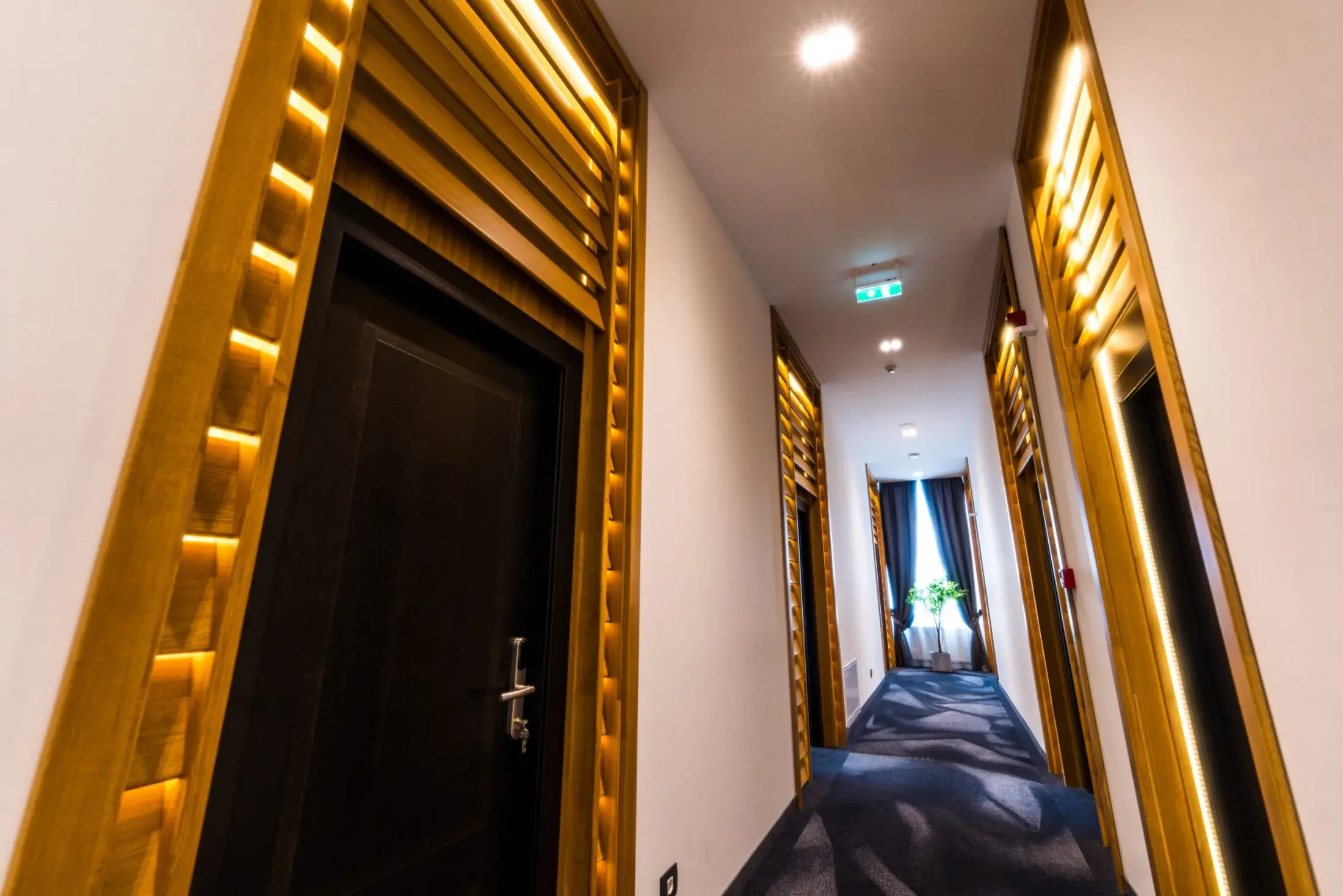 Coridor cu uși închise la culoare încadrate de lamele de stejar luminate