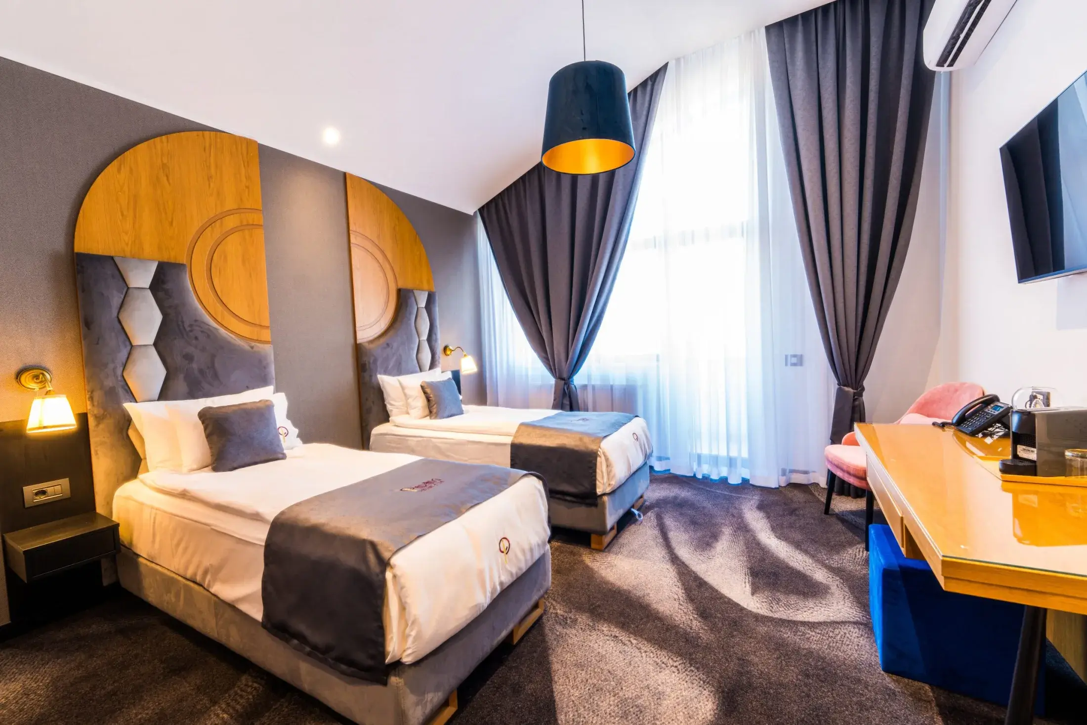 Cameră twin cu două paturi separate, tăblii cu module hexagonale și birou
