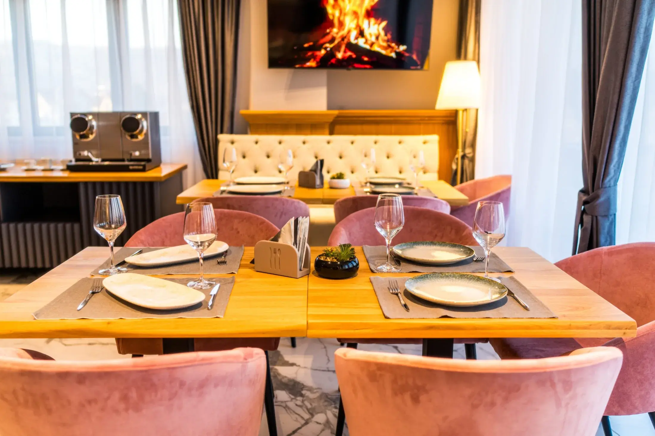 Mese din lemn de stejar și scaune roz de catifea, puse pentru cină, în restaurant