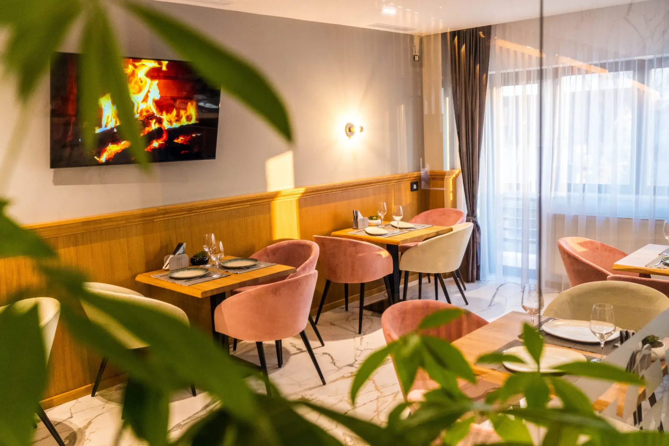 Mese pentru doi cu fotolii roz, lângă ferestrele restaurantului